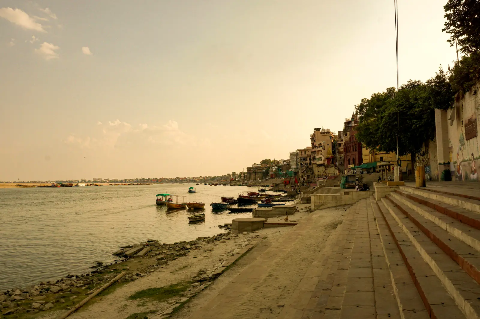 Varanasi ghats on the Ganga with moored boats and temple spire at sunrise
